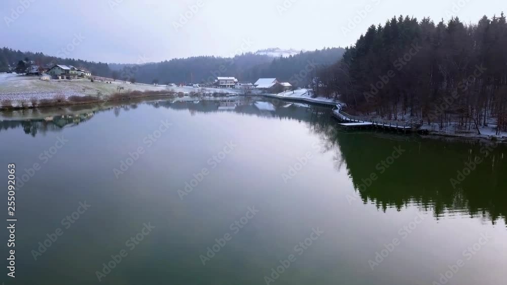 Aerial: Flying over beautiful lake with hiking path arround it on snowy day. Filming pond surroundings with drone on cold winter day. Aerial: Flying over beautiful lake with hiking path arround it on snowy day. Filming pond surroundings with drone on cold winter day.