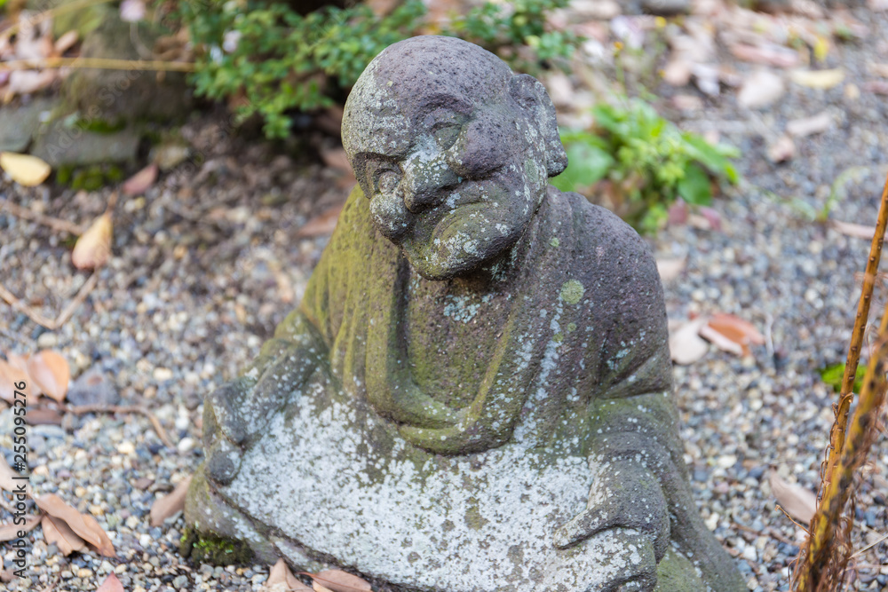 Old statue of a seated Buddhist monk made of stone close-up Old statue of a seated Buddhist monk made of stone close-up