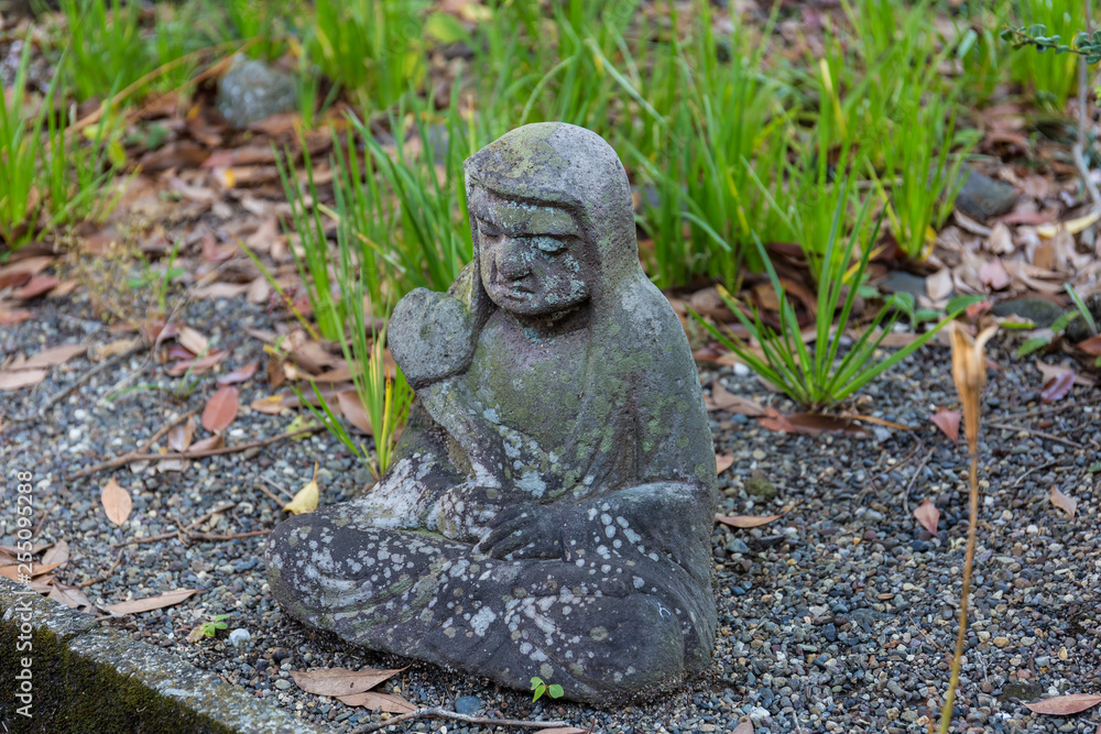 Old statue of a seated Buddhist monk made of stone close-up Old statue of a seated Buddhist monk made of stone close-up