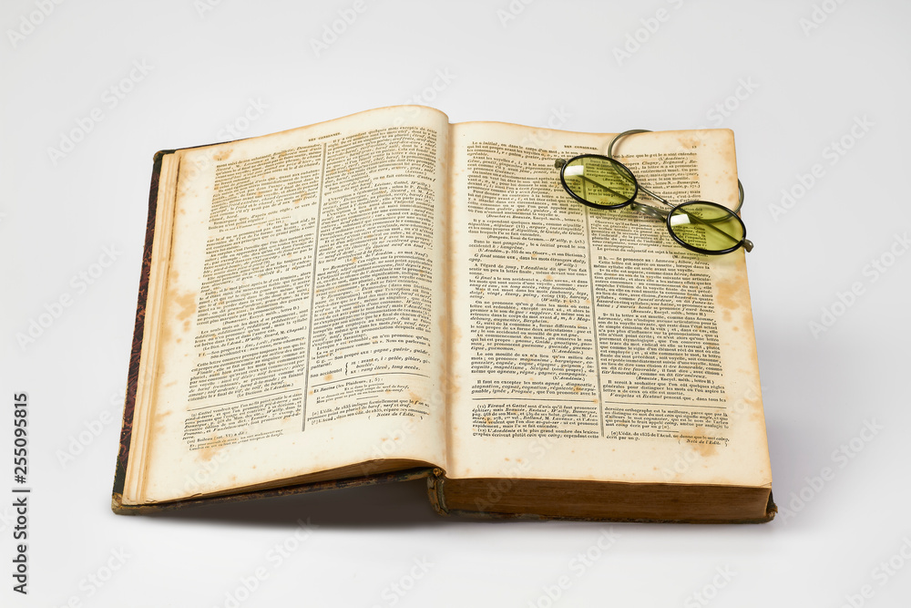 Obraz premium Old french dictionary lies open with old spectacles against a white background