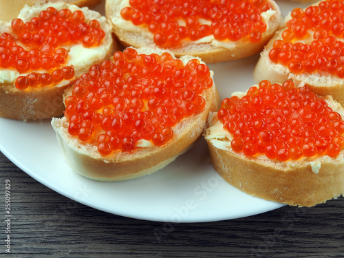 Red caviar on sandwiches on a wooden table