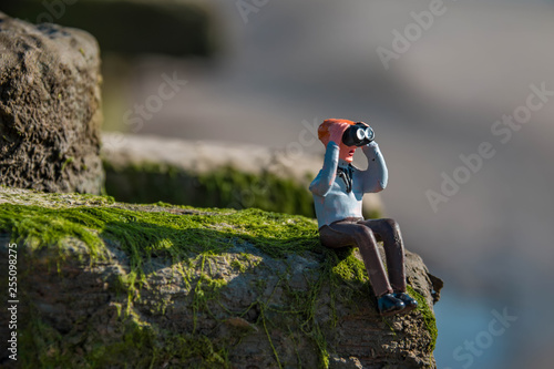 Miniatur Figur Mann sitzt im Gras und schaut durch ein Fernglas (no brand)