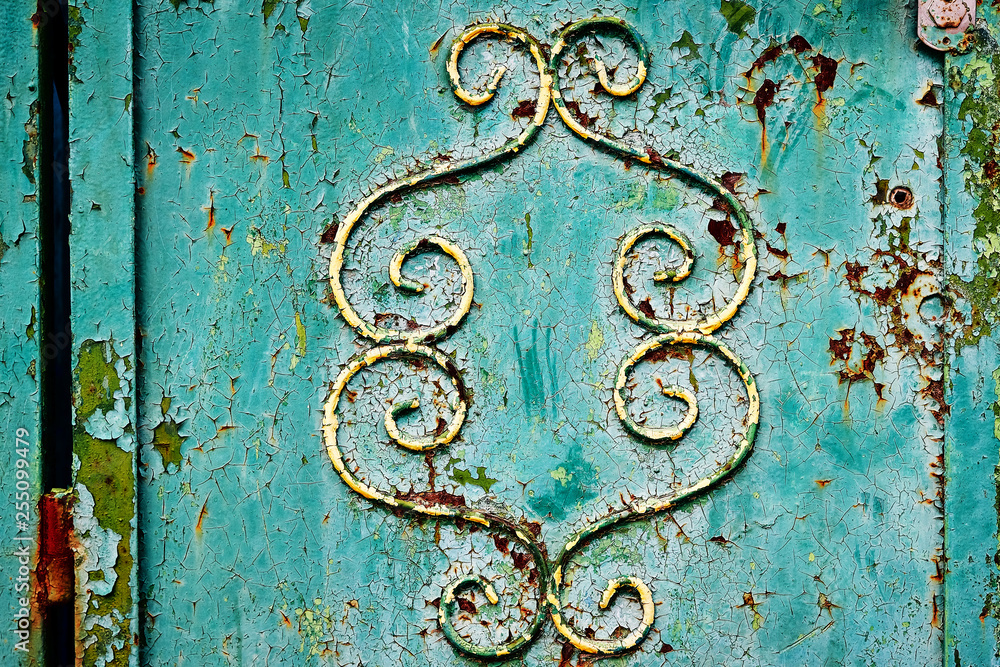 Rusty metal door with green paint and yellow curls and rust corroding, desiccation, alteration, metal corrosion, naming, flaking.