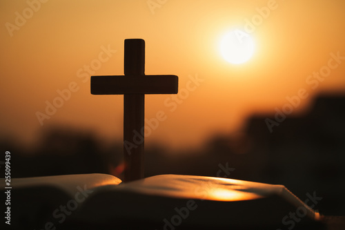 Photos Silhouette of the wooden cross over opened bible with a bright sunrise as background , Christian, god