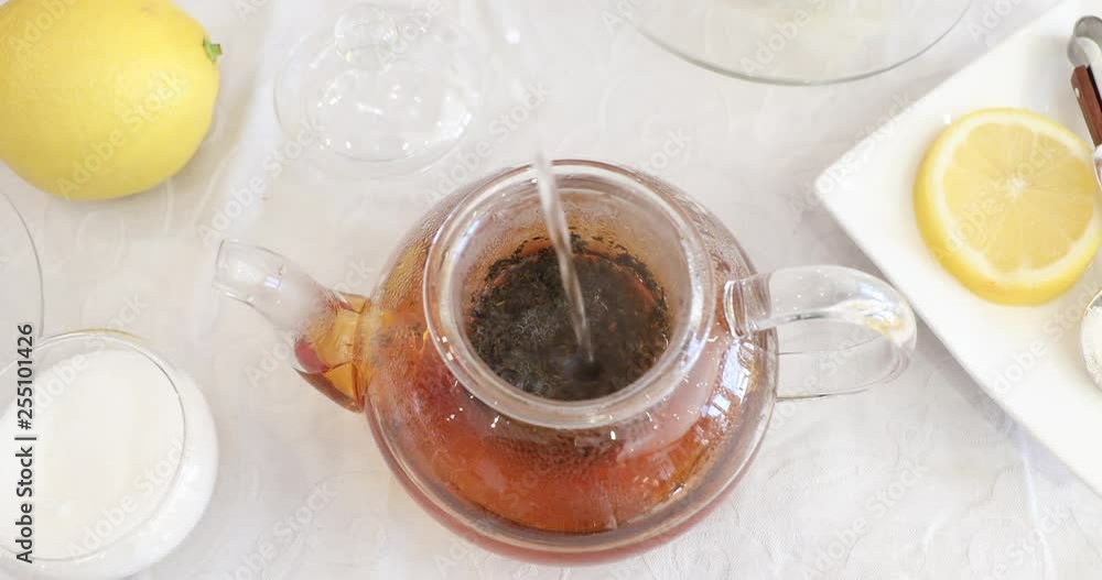 Pouring water into glass teapot to make lemon black tea Pouring water into glass teapot to make lemon black tea