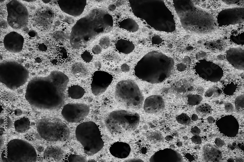 The holes on the porous sponge for washing dishes close up black and white photo