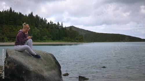 girl is having fun looking into the smartphone on the background of the lake and lakes