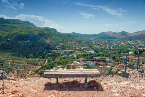 Top view from the ancient fortress on the Old Bar in Montenegro. Landscape with mountains and sky. In the center of the frame is a wooden bench.