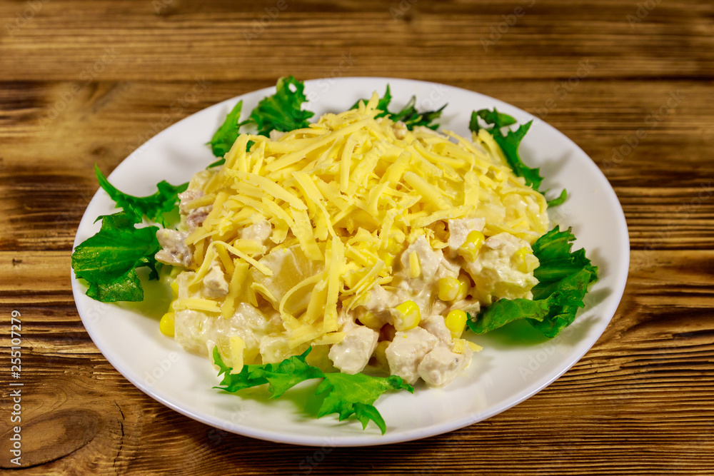 Festive salad with chicken breast, sweet corn, canned pineapple, cheese and mayonnaise on wooden table Festive salad with chicken breast, sweet corn, canned pineapple, cheese and mayonnaise on wooden table