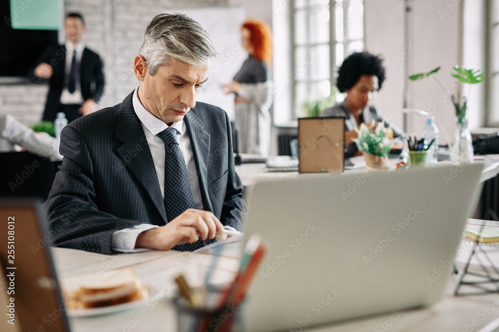 Mid adult manager doing paperwork while working at office desk. Mid adult manager doing paperwork while working at office desk.