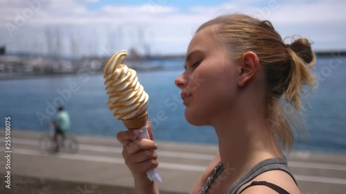 beautiful girl eats a sexy big ice cream cone on the coast