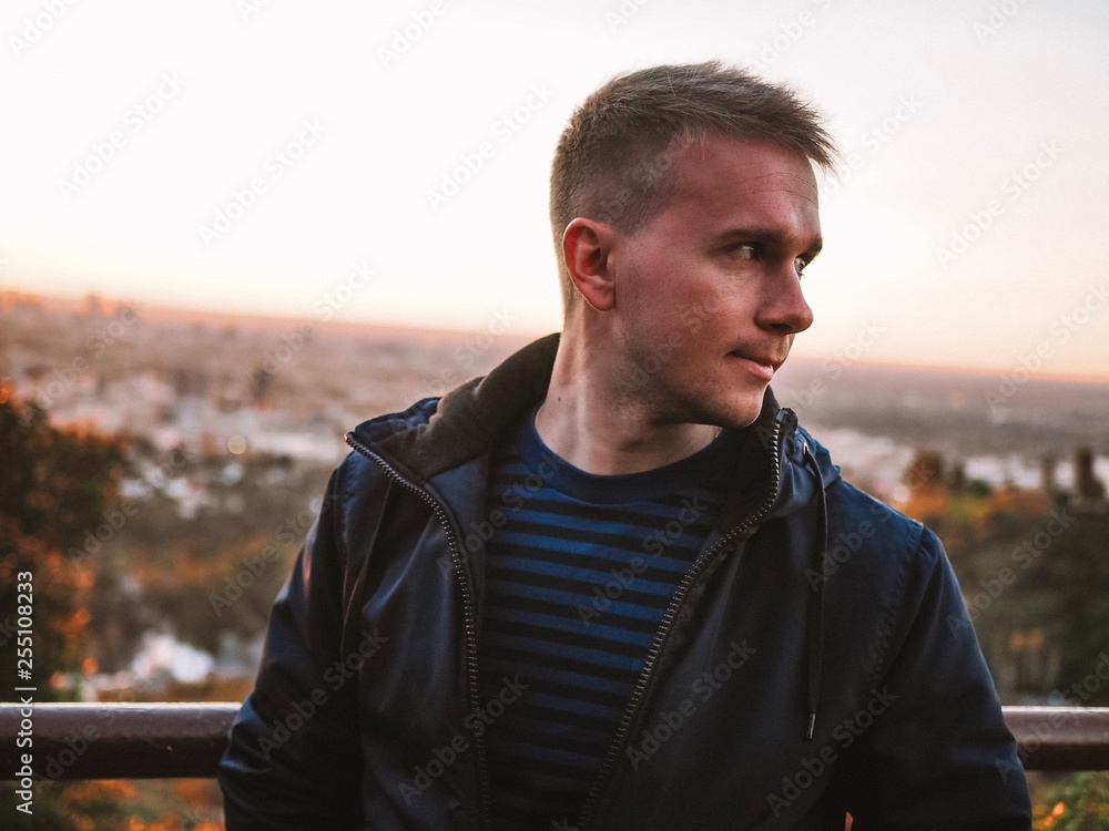 A blond man stands in the rays of the rising sun with a view of the panorama of the morning Los Angeles A blond man stands in the rays of the rising sun with a view of the panorama of the morning Los Angeles