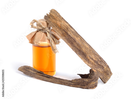 Agarwood, also called aloeswood oudh. With essential oil in pharmaceutical bottle. Isolated on white background photo