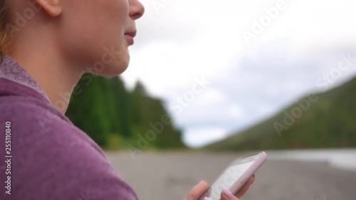 girl singing on the shore of the lake in nature listening to music on a smartphone
