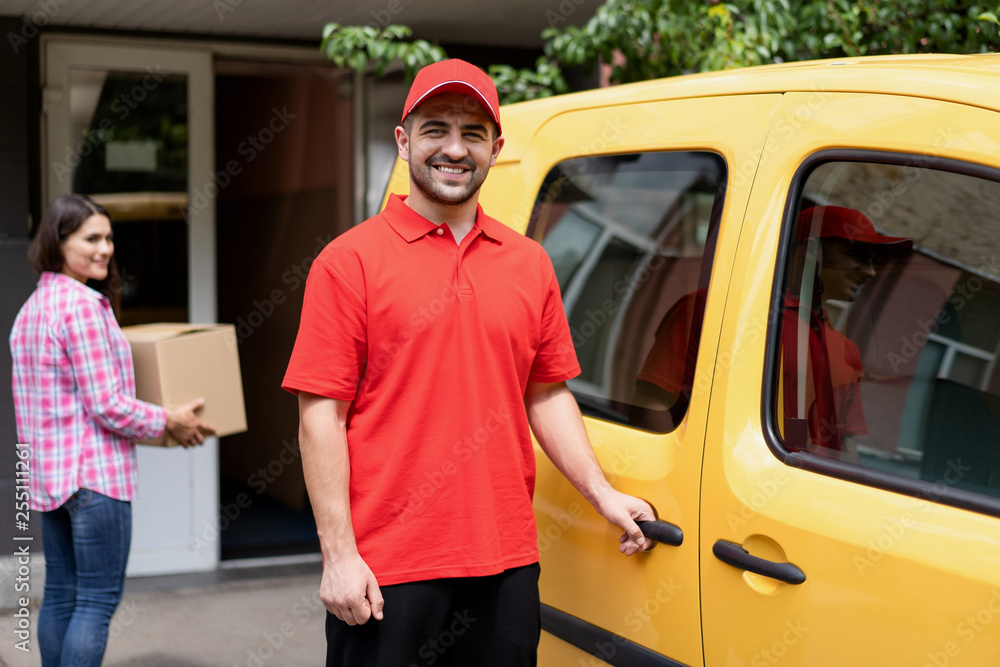 Smiling delivery guy standing near yellow van. Smiling delivery guy standing near yellow van.