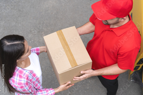 Courier is giving delivery parcel to young woman. Top view photo