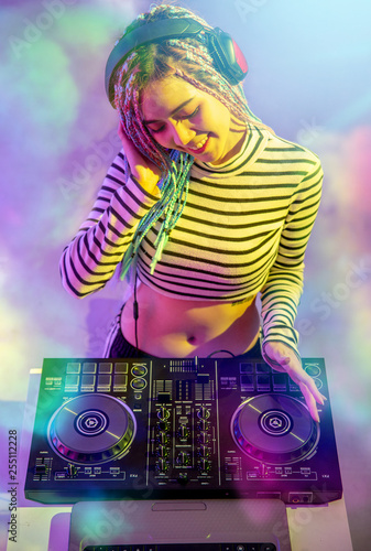 Asian girl DJ is playing a turntable in night party is colorful.