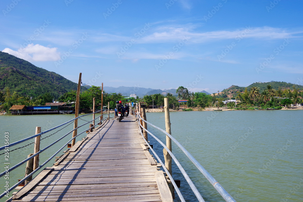 wooden bridge across the river  with motorbikes traveling along it, Vietnam