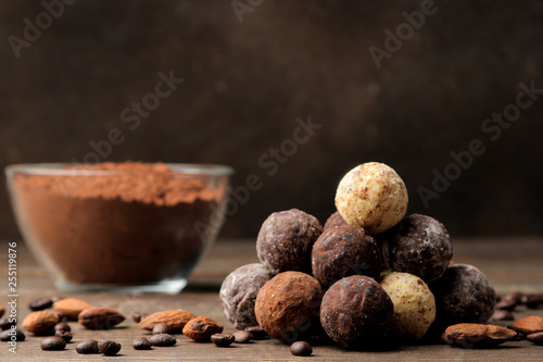 assorted chocolates. candy balls of different types of chocolate on a brown wooden table. cinnamon and almonds