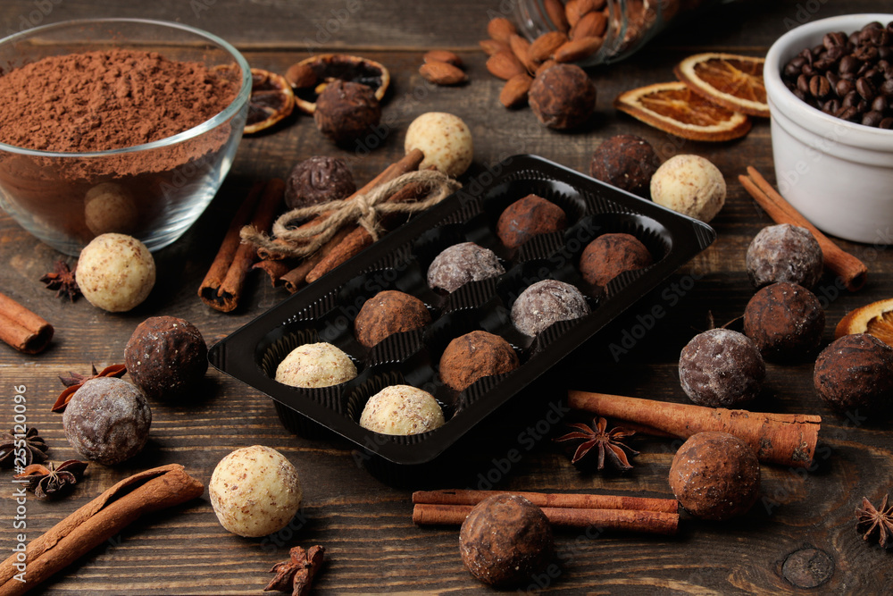 assorted chocolates. candy balls of different types of chocolate on a brown wooden table. cinnamon and almonds.
