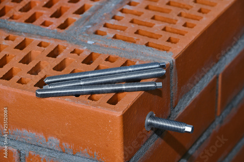  set of parts for mounting anchors in hollow brick and concrete lie on the surface of the brickwork in any order. Threaded studs.