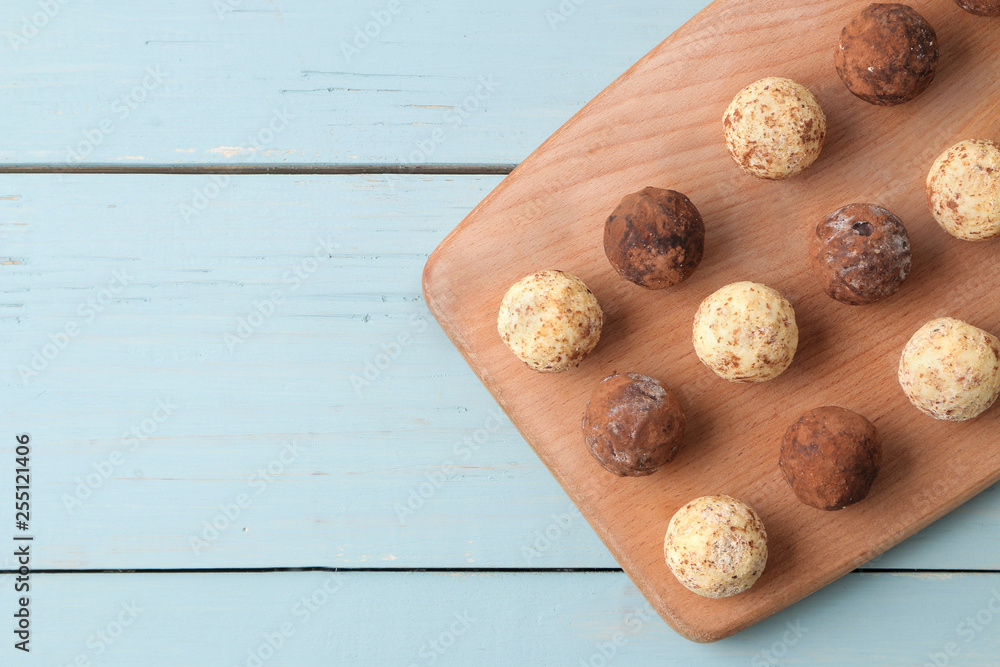 assorted chocolates. Candy balls of different types of chocolate on a wooden board on a blue wooden table. top view
