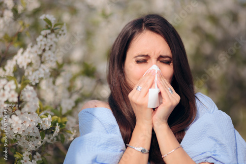 Allergic Woman Blowing Her Nose Next to Blooming Tree