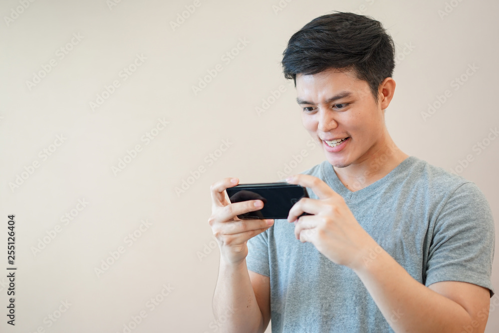 close up young asian man playing online game application with feeling excited in relax time , millennial life concept close up young asian man playing online game application with feeling excited in relax time , millennial life concept