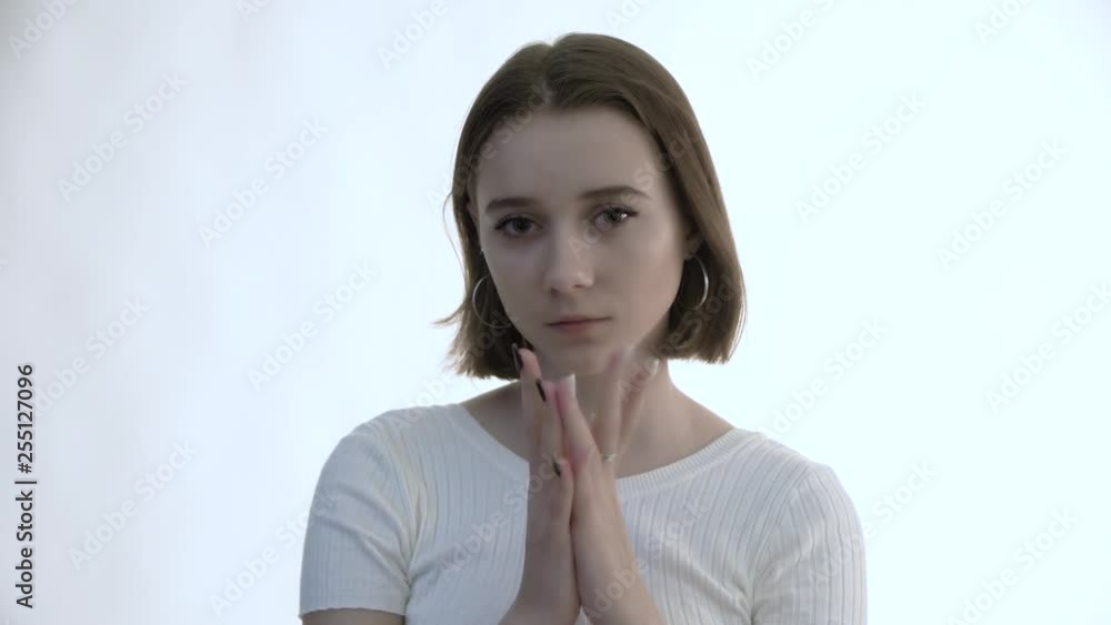 Young beautiful woman cover his face by the hands and his eyes looks at you Young beautiful woman cover his face by the hands and his eyes looks at you
