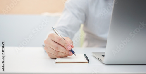 close up businessman hand writing content or somethings on notebook with using laptop at office home , lifestyle concept