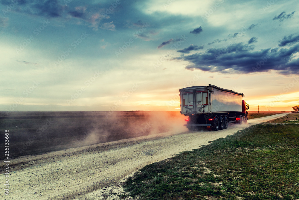Fototapeta premium Truck on road with setting sun the background