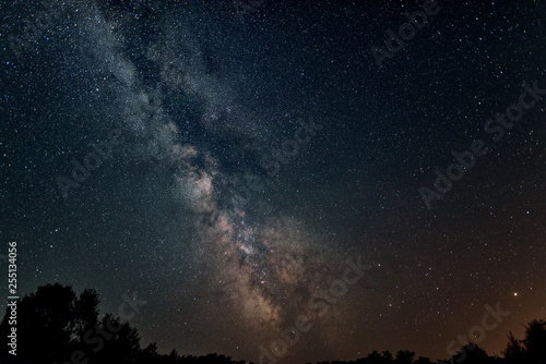 Clear night sky with a hill and trees in the foreground Milky Way night sky stars shooting stars