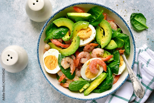Avocado salad with baby spinach, shrimps and boiled eggs.Top view with copy space.