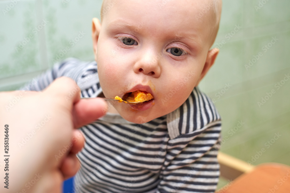 Parent feeds baby a pumpkin with a spoon Parent feeds baby a pumpkin with a spoon