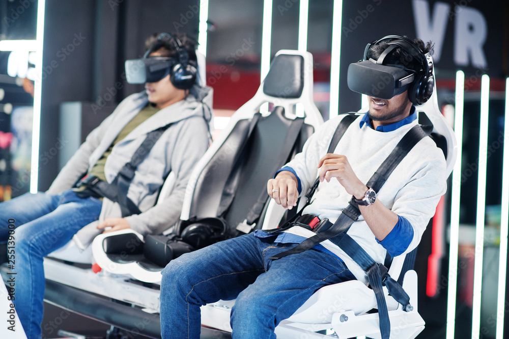 Two young indian people having fun with a new technology of a vr headset at virtual reality simulator. Two young indian people having fun with a new technology of a vr headset at virtual reality simulator.