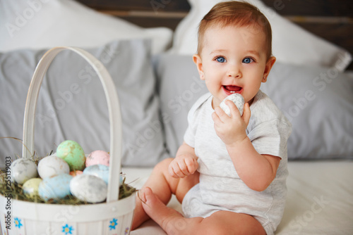 Portrait of baby eating easter egg in bed