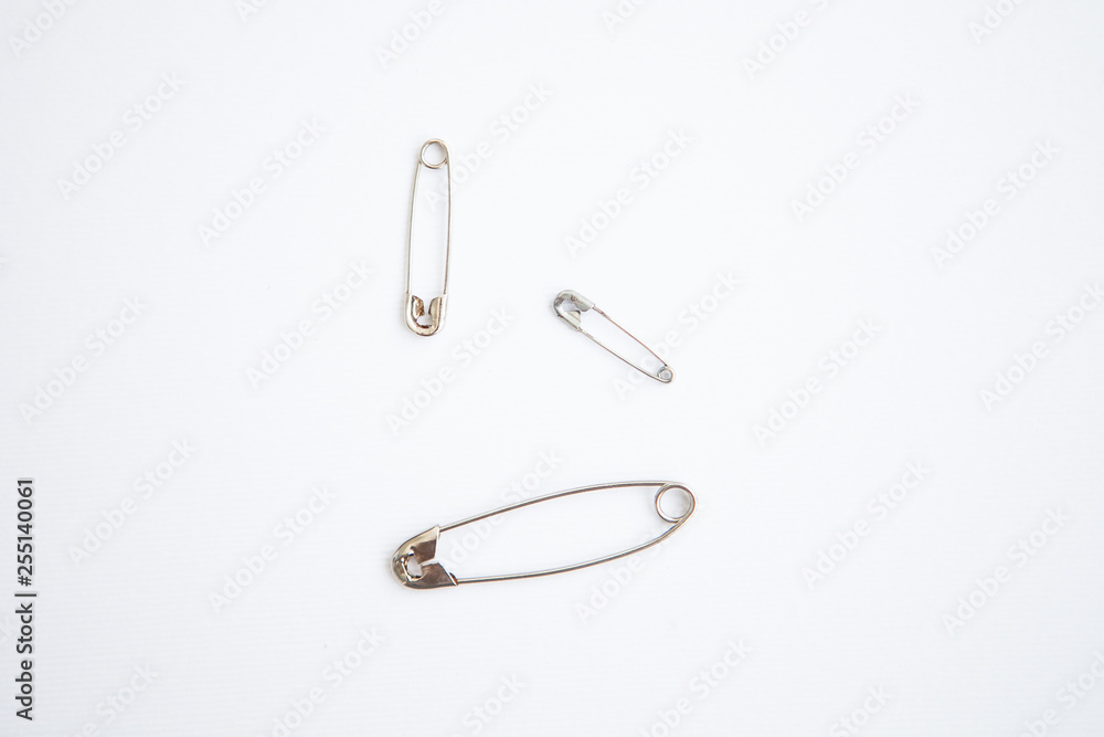 Three safety pins on a white ground