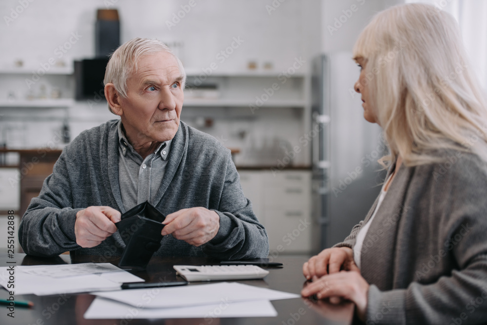 senior couple sitting at table with documents and wallet senior couple sitting at table with documents and wallet