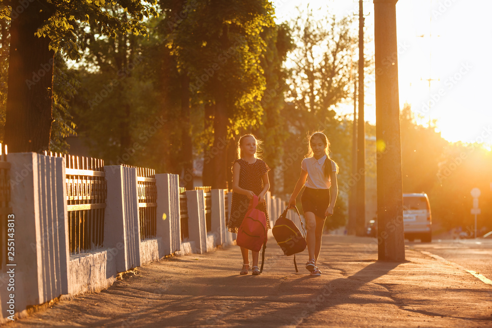 Two child girls is walking with a school bag in sunny day