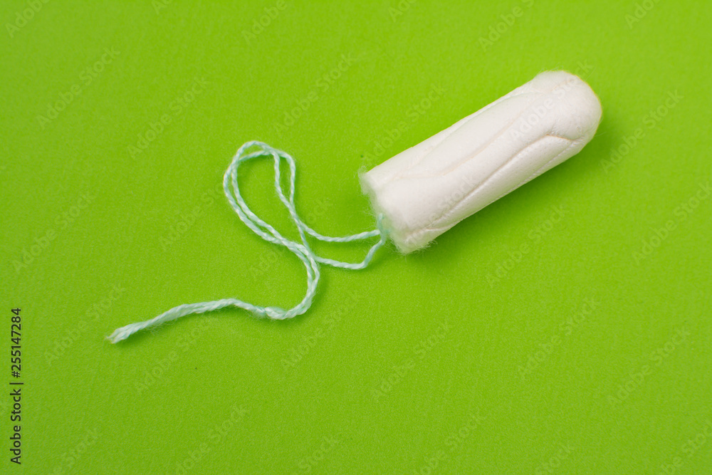 one cotton swab on a menstrual pad on a green background. Girl cycle period concept. Women's days hygiene protection. Top view, flat lay. one cotton swab on a menstrual pad on a green background. Girl cycle period concept. Women's days hygiene protection. Top view, flat lay.
