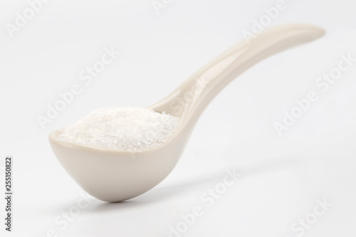 A creamy ceramic spoon with sugar