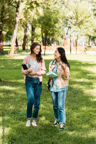 pretty girls holding books and looking at each while talking in park © LIGHTFIELD STUDIOS