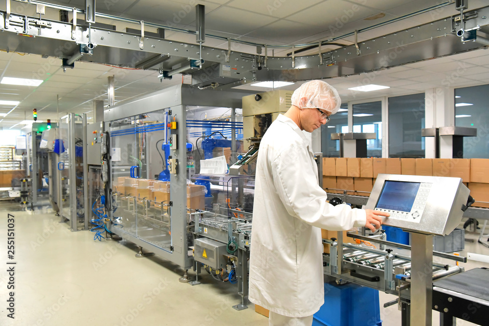 Arbeiter in Schutzkleidung am Fliessband für den Versand Pakete von verpackten Medikamten in einem Pharmaunternehmen // Conveyor belt worker for shipping parcels of packaged medications in a pharmaceu Arbeiter in Schutzkleidung am Fliessband für den Versand Pakete von verpackten Medikamten in einem Pharmaunternehmen // Conveyor belt worker for shipping parcels of packaged medications in a pharmaceu