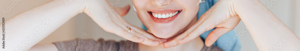 Fototapeta premium Close up shot of glad satisfied woman being happy after spa procedure, has fresh soft healthy skin, broad smile, white perfect teeth touch her face look at camera. long banner