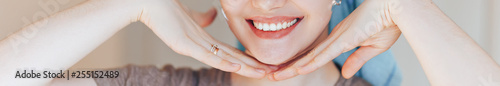 Close up shot of glad satisfied woman being happy after spa procedure, has fresh soft healthy skin, broad smile, white perfect teeth touch her face look at camera. long banner