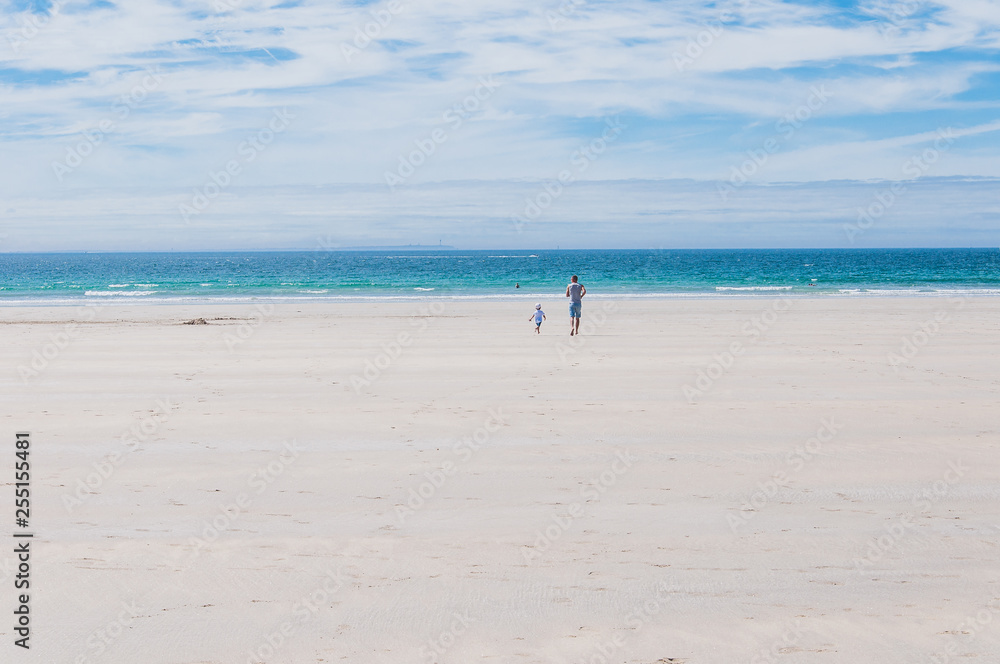 Father and son running towards the Atlantic Ocean on the beach in Finistere France