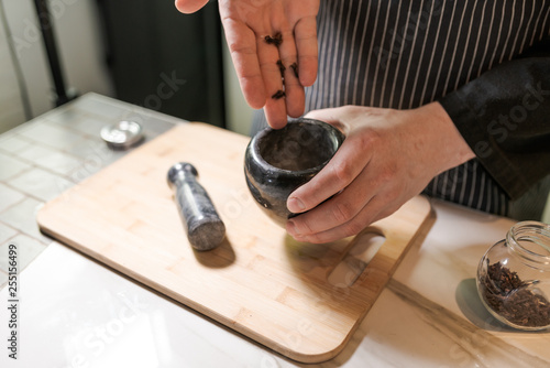 A man is grinding spices with a mortar and pestle.