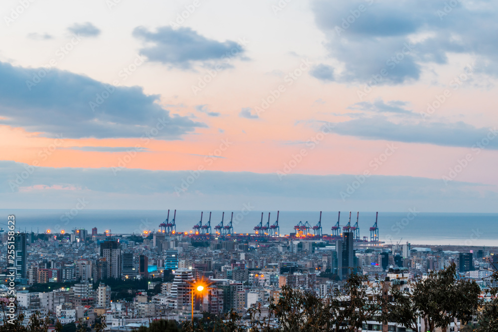 Fototapeta premium Jest to uchwycenie zachodu słońca w stolicy Libanu w Bejrucie z ciepłym pomarańczowym kolorem i chłodną chmurą, a na zdjęciu widać port w Bejrucie.