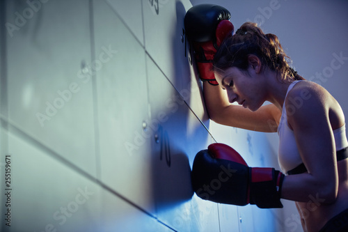Below view of exhausted female boxer in locker room.