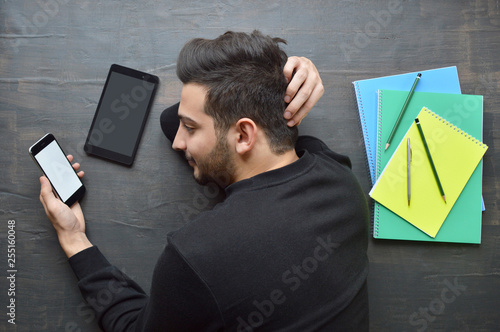 Young man using smart phone instead of studying
